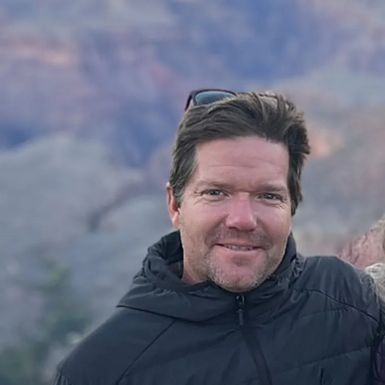 Stephen Conklin, smiling, on the rim of the Grand Canyon at sunset